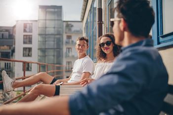 Three people are sitting on a balcony.